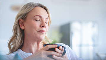 Woman enjoying a calm moment with coffee, feeling balanced through menopause
